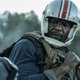 Terry Crews, sitting on a motorcycle with a helmet on, recoils from an unseen passenger in his sidecar.